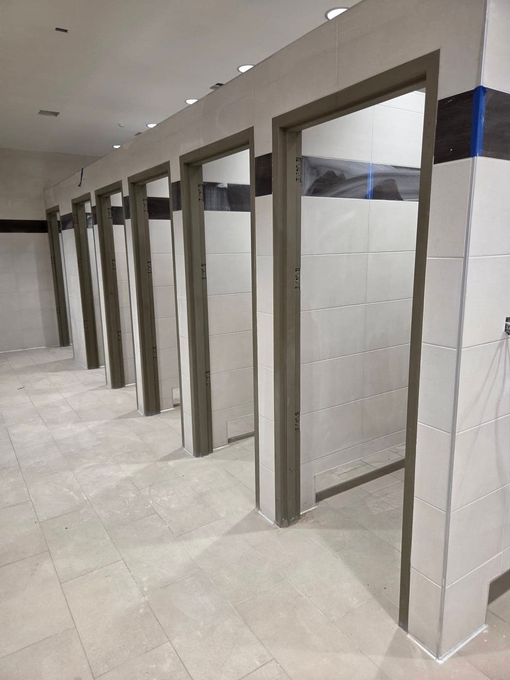 Commercial restroom with a row of stall partitions freshly painted dark gray